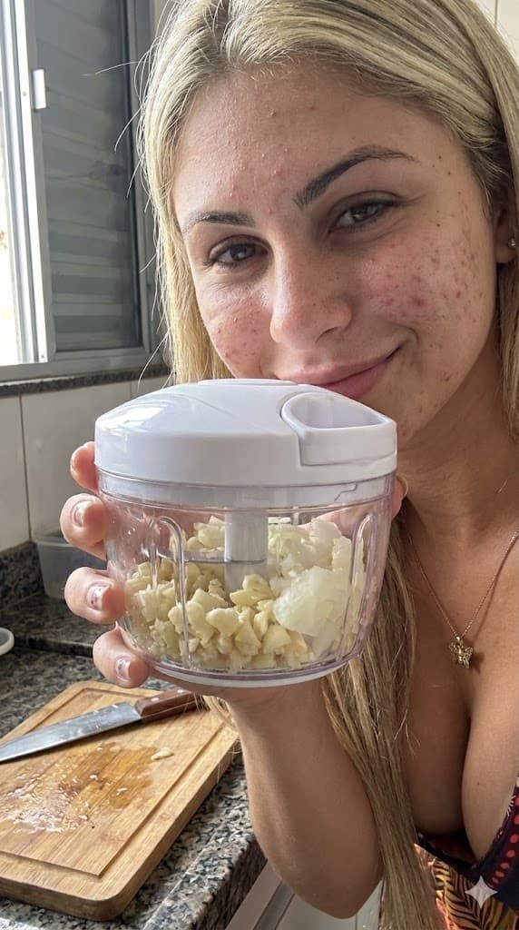 Mãos da Isabelle usando o mini processador para triturar cebola e alho